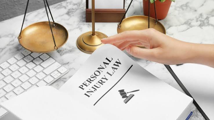 A hand turning the page of a book titled Personal Injury Law next to a scale of justice, representing Personal Injury Doral Florida legal services.
