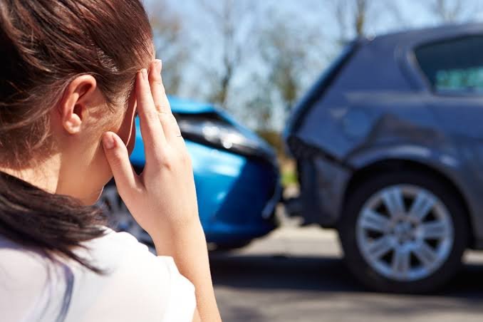 A distressed female driver, viewed from behind with her hand on her head, looks at a blue car and a grey car damaged in a rear-end collision, highlighting a situation where a Car Accident Claim Attorney can offer vital legal support