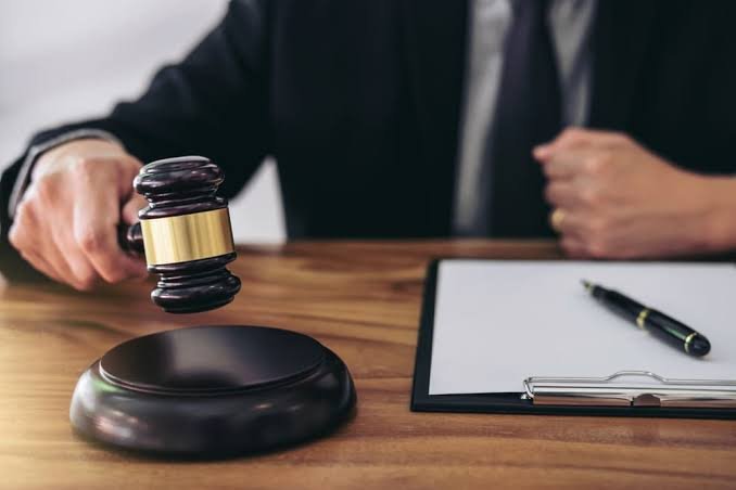 An attorney holding a wooden gavel beside a clipboard on a wooden desk, representing a Personal Injury Settlement Lawyer.