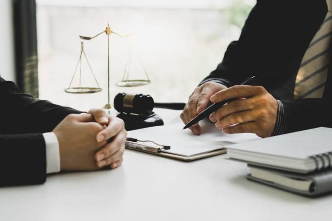 An attorney taking notes during a client consultation beside scales of justice, representing a Severe Personal Injury Lawyer.