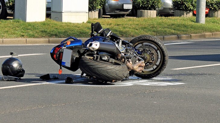 Damaged blue motorcycle on its side and a helmet on the asphalt after a Motorcycle Accident Miami Florida.