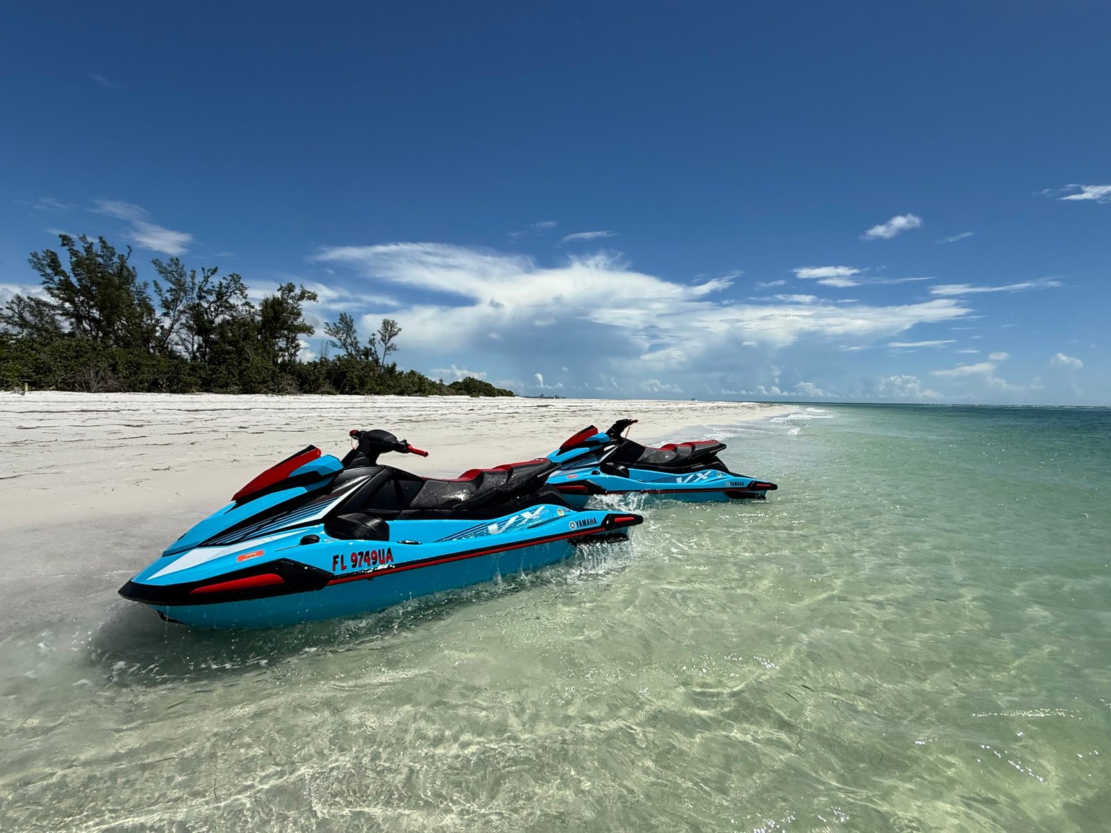 Two blue personal watercraft parked on a sunny Florida beach, illustrative of watercraft recreation safety and scenarios requiring a jet ski accident lawyer.